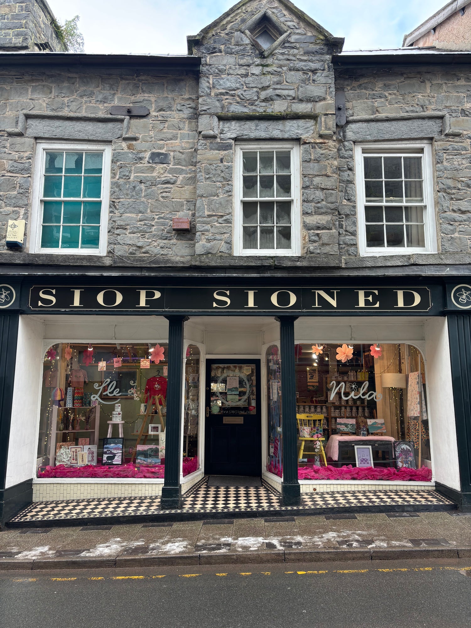 Storefront with sign and display windows in a stone building.